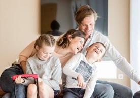 A happy family made of two adults and two kids in the living room of a holiday flat